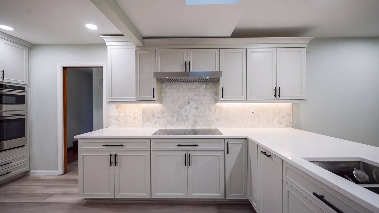 Cooktop and range hood surrounded by white cabinetry