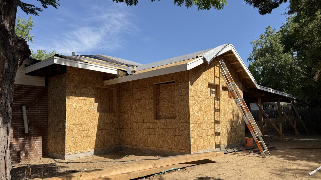 Attached living space under construction beside an existing brick home