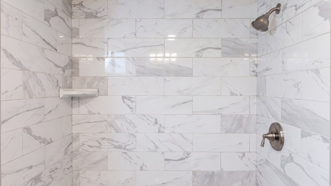 Shower walls with veined white tile and a built-in niche