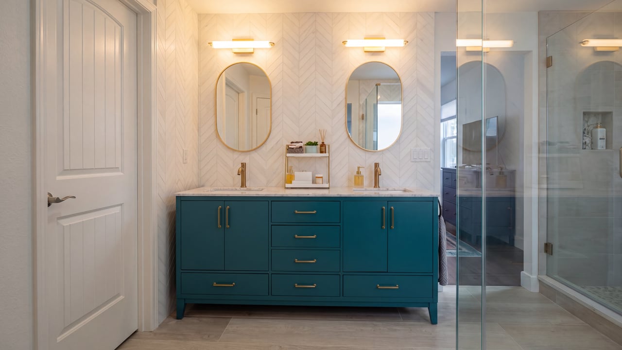 Teal double vanity with oval mirrors and wall sconces