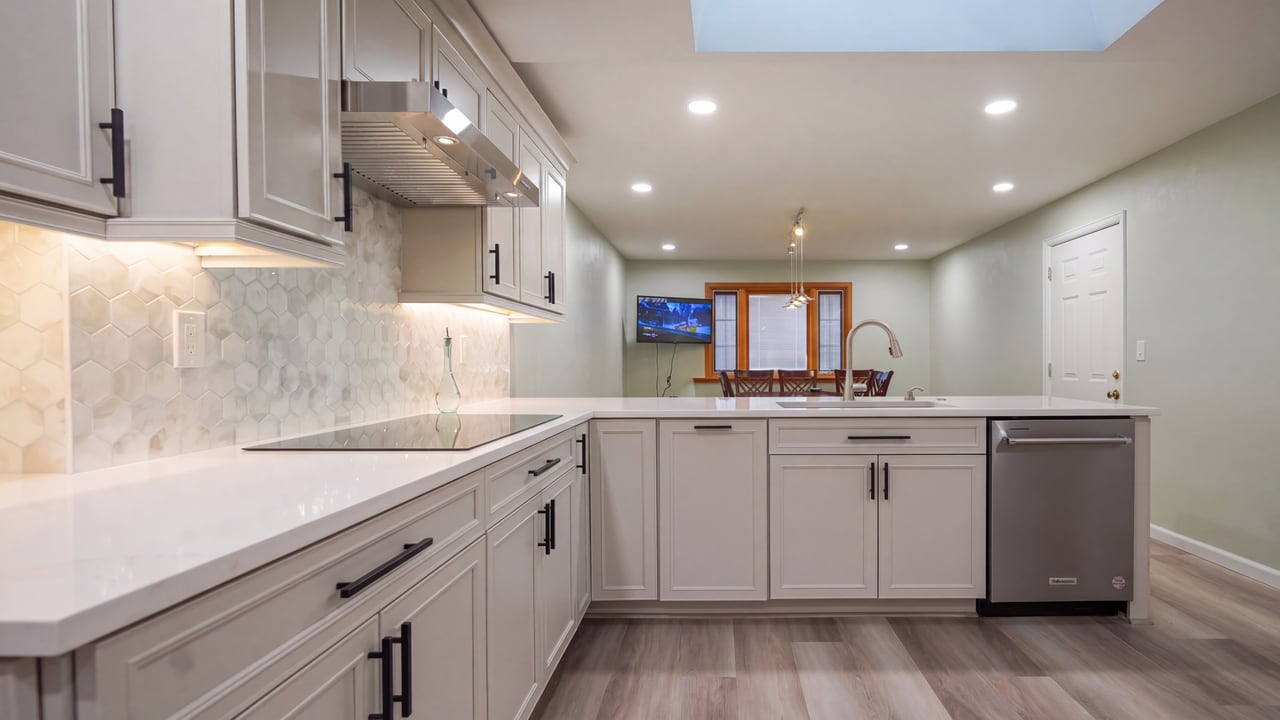 Illuminated backsplash beneath white kitchen cabinets