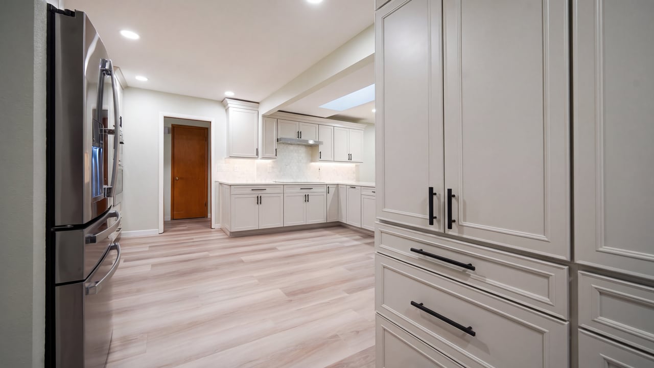 White kitchen cabinetry, full-height storage, and pale wood flooring