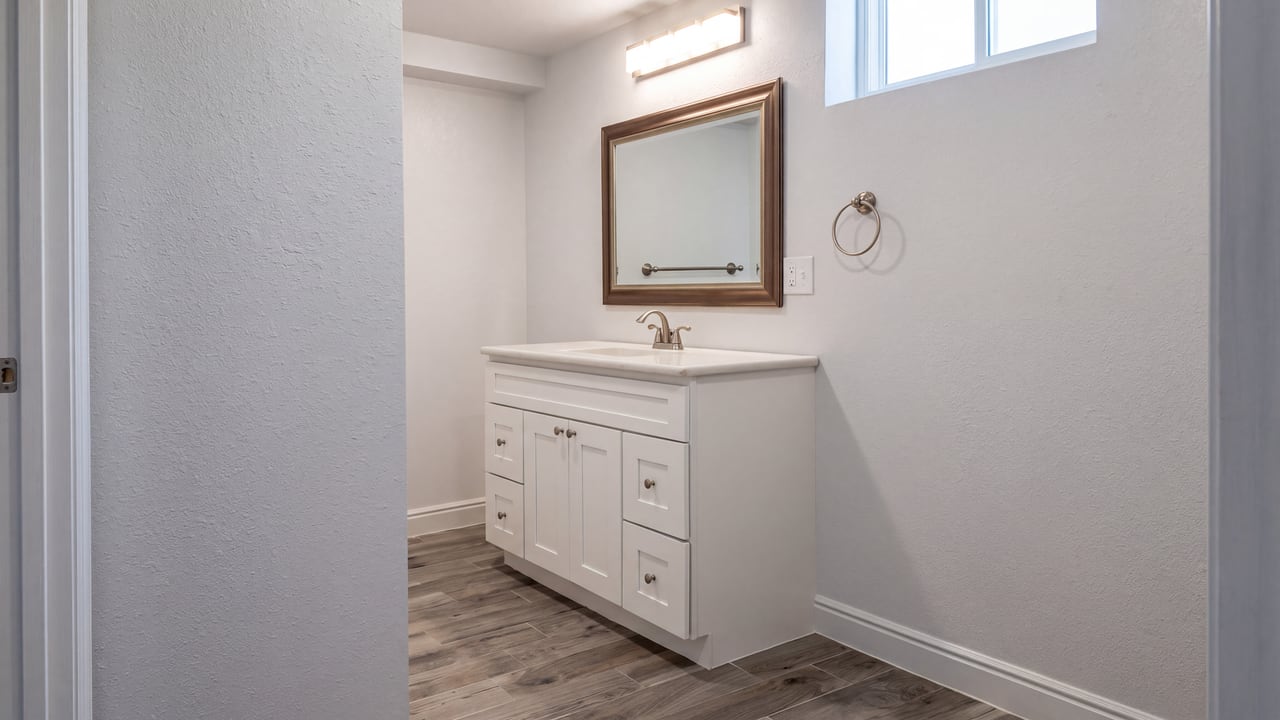 White bathroom vanity beneath a framed mirror